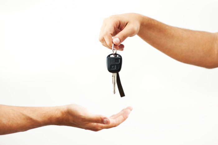 Hand gives car keys to a receiving hand who borrows car