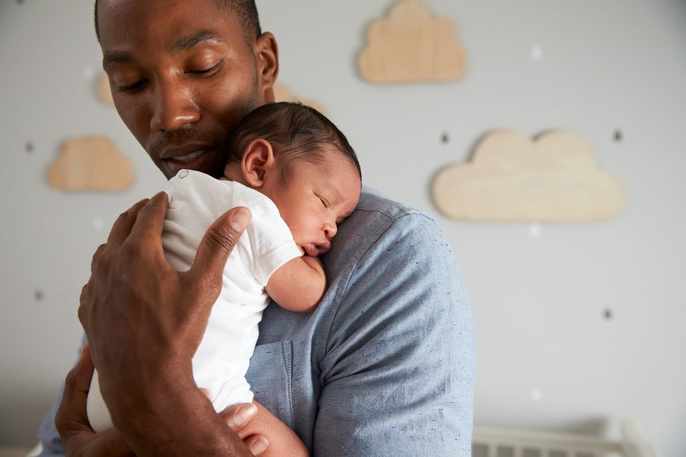Father Holding Newborn Baby In Nursery