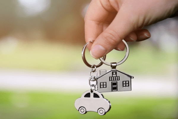 Hand holding house and car keychains