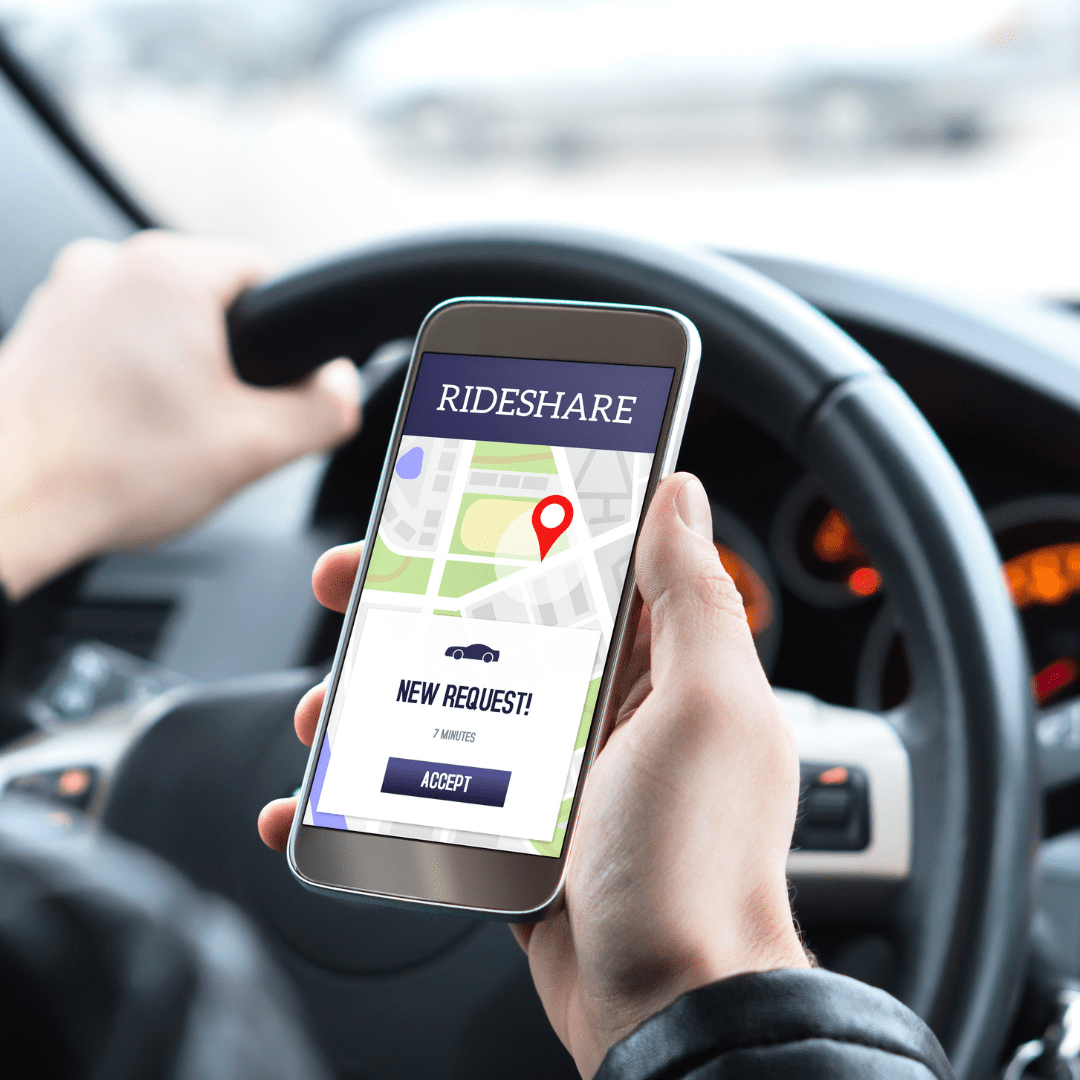 Person sitting behind a car's steering wheel with a rideshare map on a cellphone.