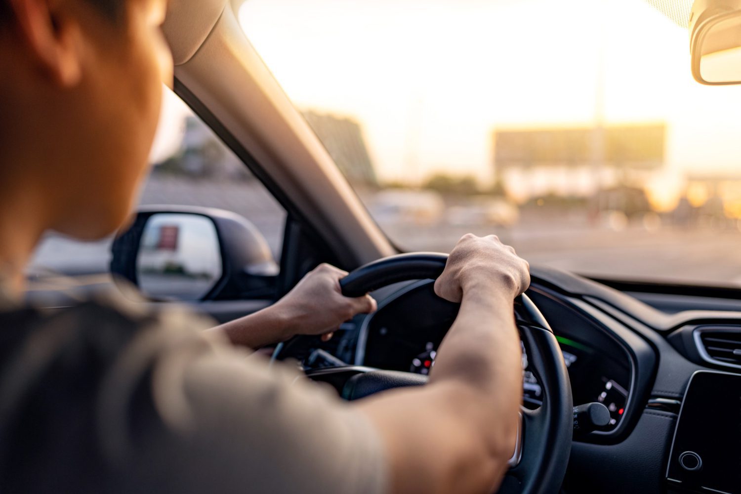 A man driving a car with his hands on the steering wheel.