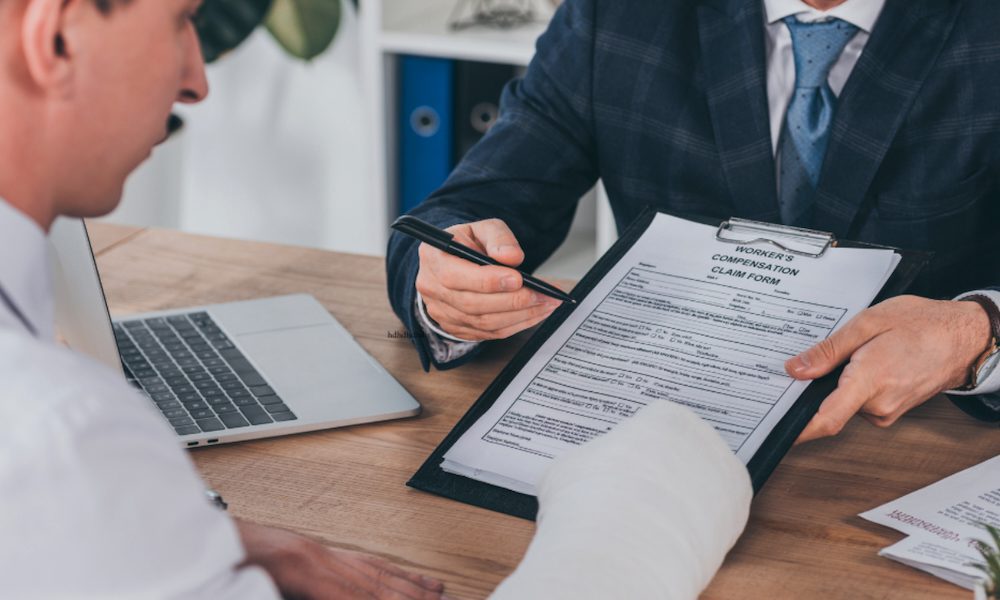 Blog post - Injured employee with arm cast reviewing workers’ compensation claim form with insurance agent in office setting - workers’ comp insurance for small businesses in Pennsylvania