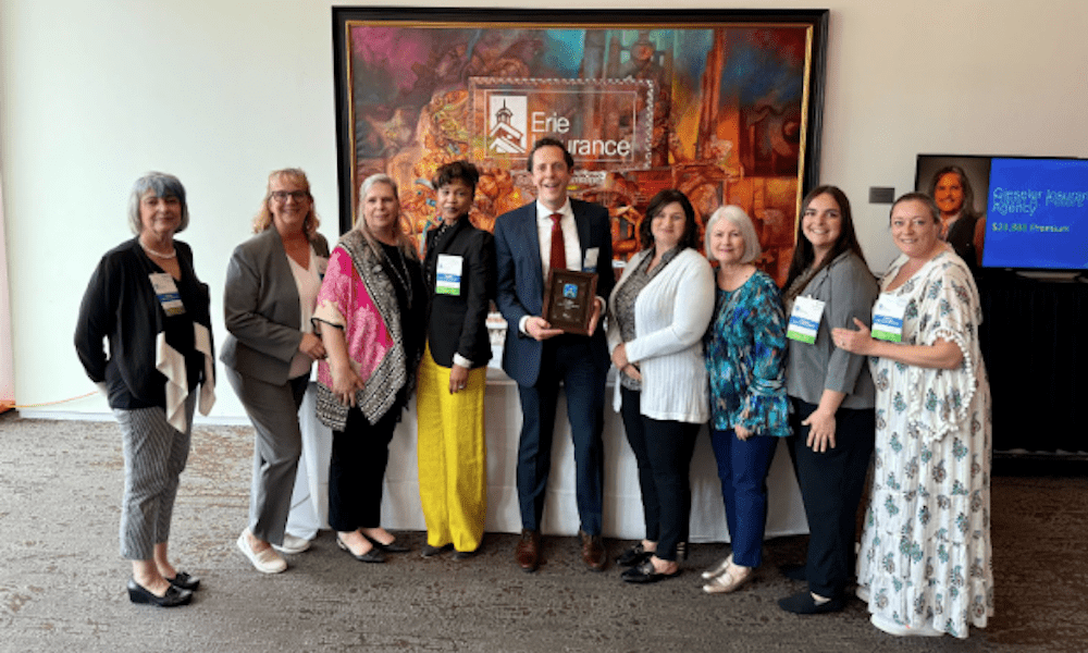 YMI Insurance team smiling and holding the District Life Award at Erie Insurance’s Annual Branch Meeting inside the ArtsQuest venue in Bethlehem, PA.