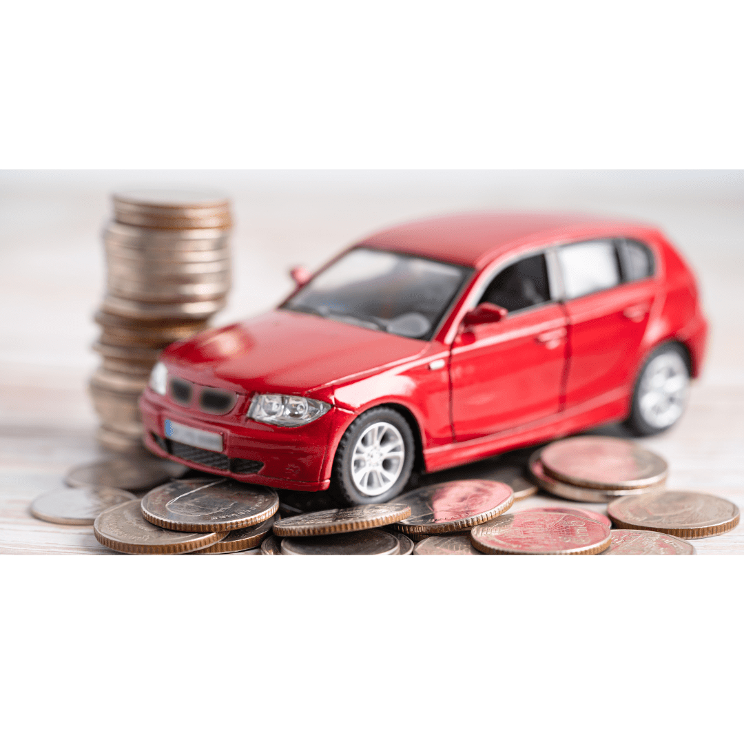 Close-up of a red toy car surrounded by stacks and piles of coins, symbolizing car insurance costs and savings.