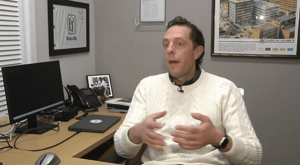 Jimi Honochick speaking during a WFMZ news interview, seated at his office desk in a cream-colored sweater and gesturing while discussing homeowner insurance coverage.